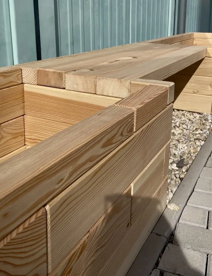 Close-up of a wooden bench on a raised bed made of larch pieces by gravel