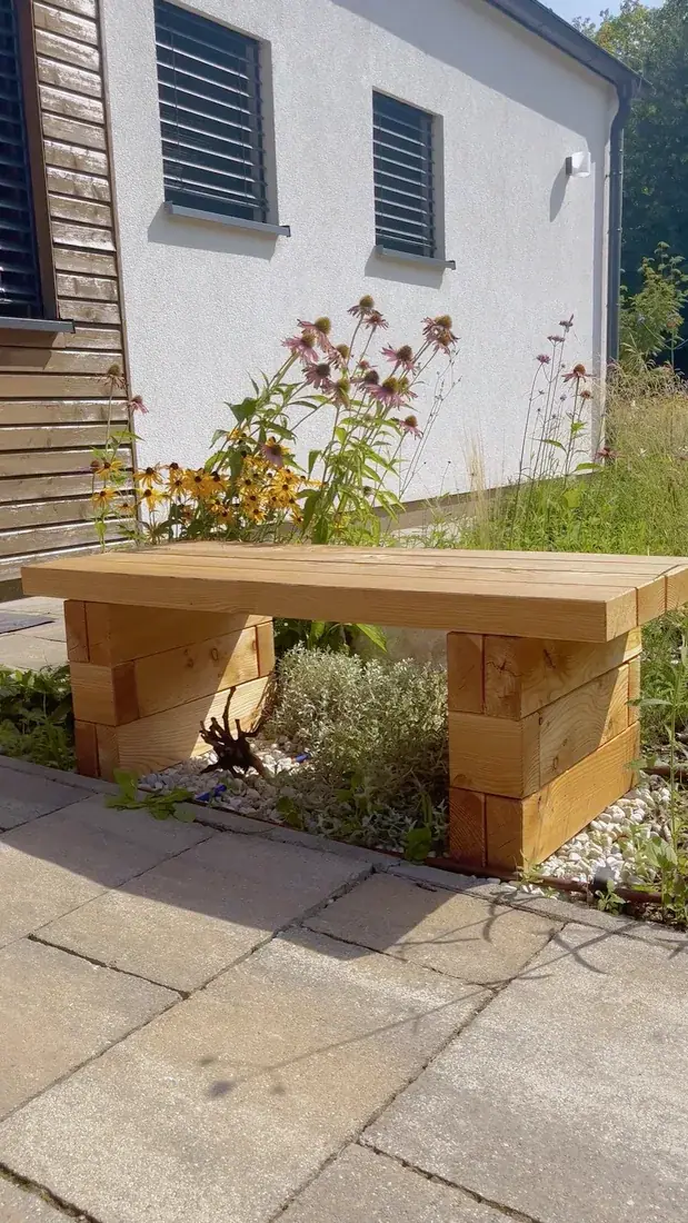 Wooden bench made of larch pieces on paving by a house
