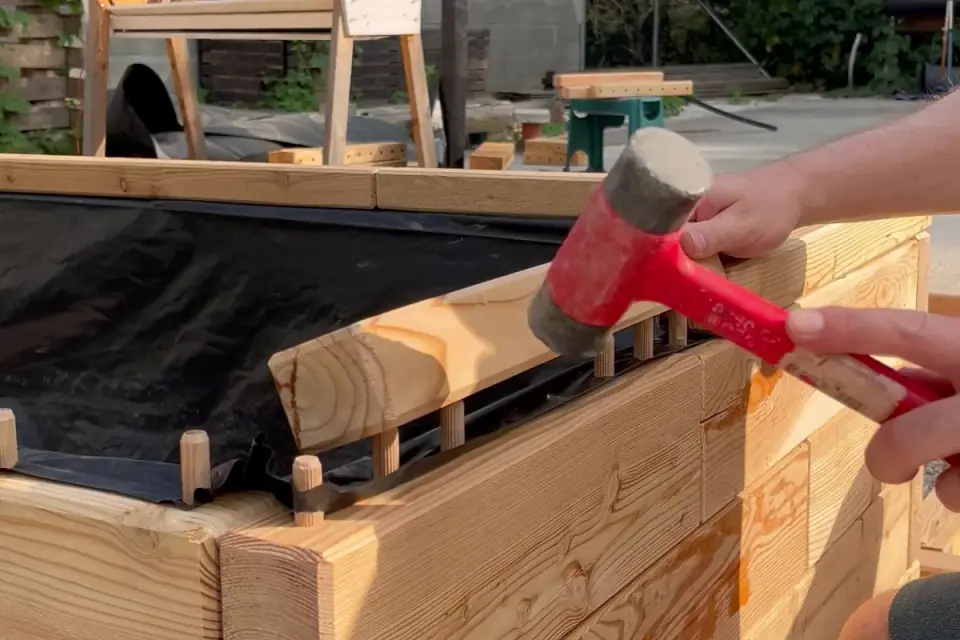 Tapping wooden dowels in with a rubber mallet while assembling a raised bed