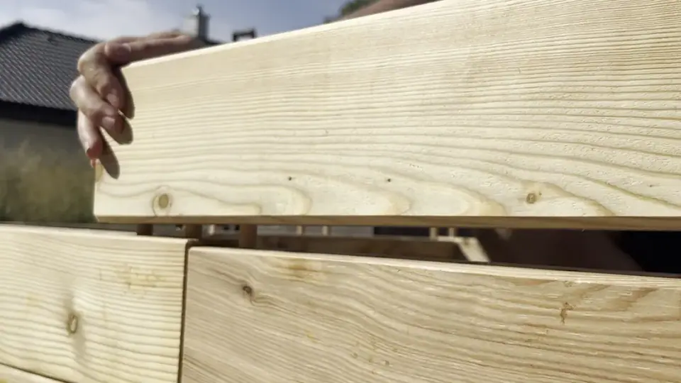 A hand placing a wooden piece during bed assembly